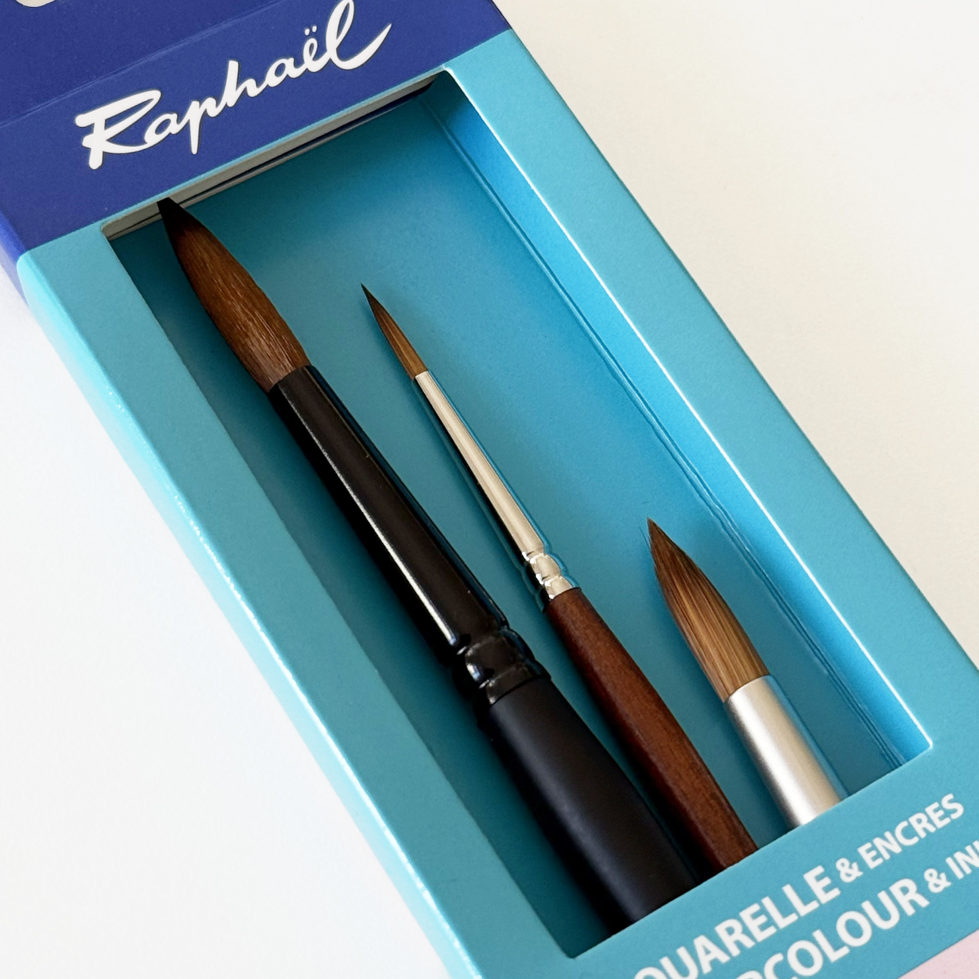 Trois pinceaux Raphaël pour l’aquarelle présentés dans leur étui bleu.